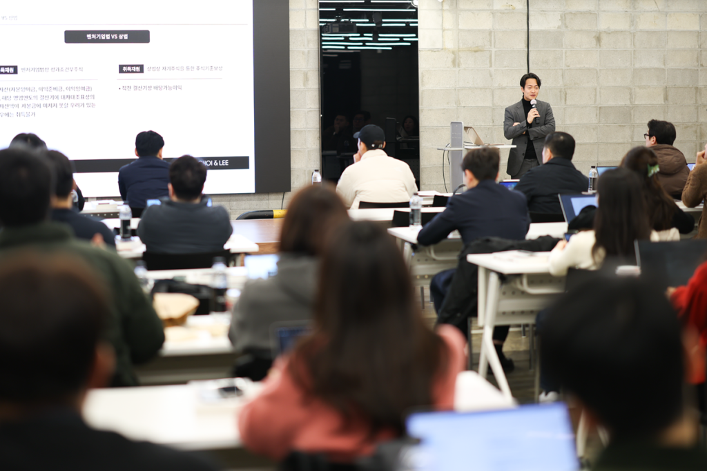 세미나 현장에서 필기하며 집중하는 참석자들.